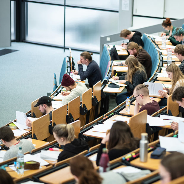 Students sit in the lecture hall and actively participate in the lecture