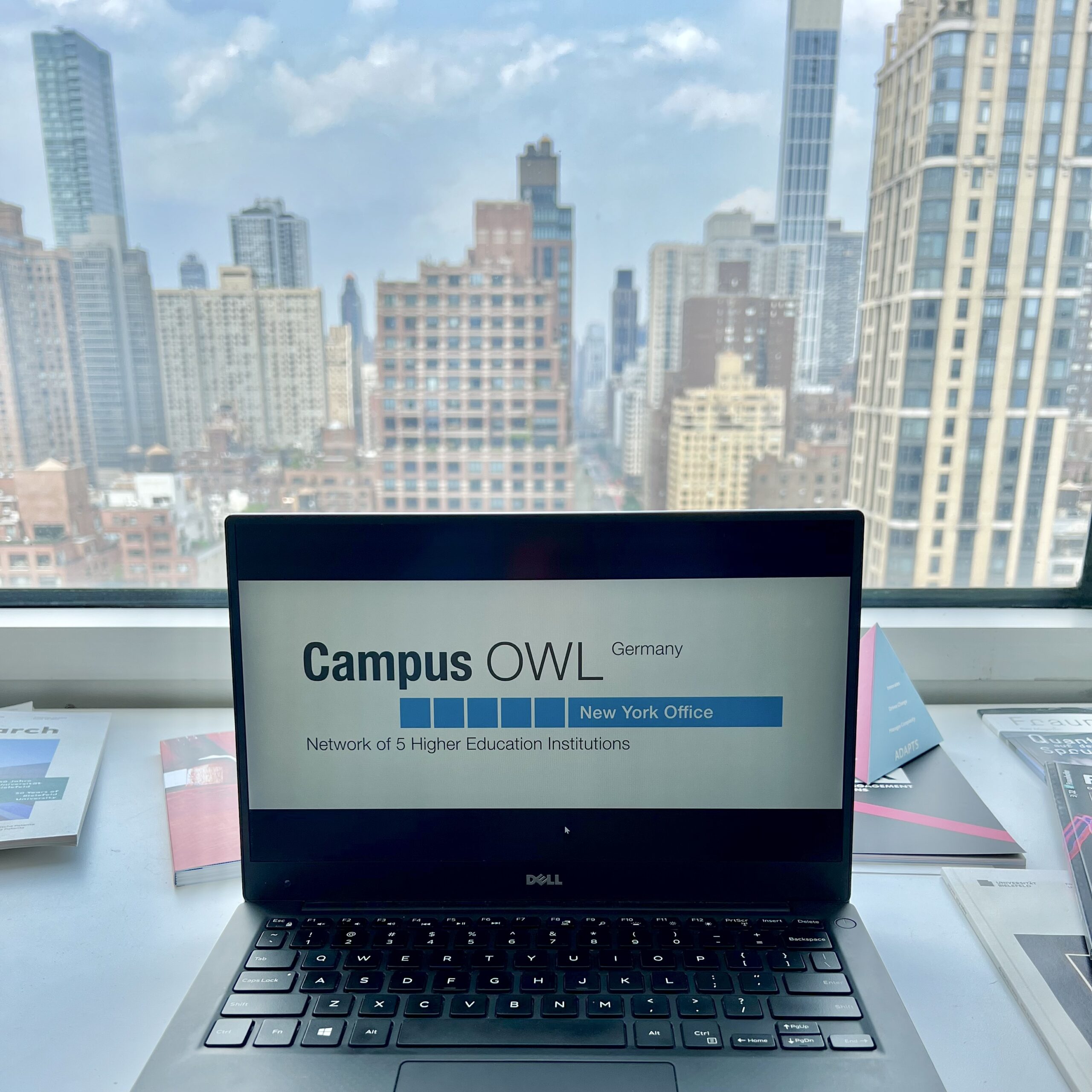 A laptop with Campus OWL logo in front of New York skyline
